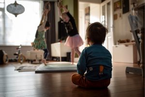 Two young girls dancing while a little boy is turned away watching them